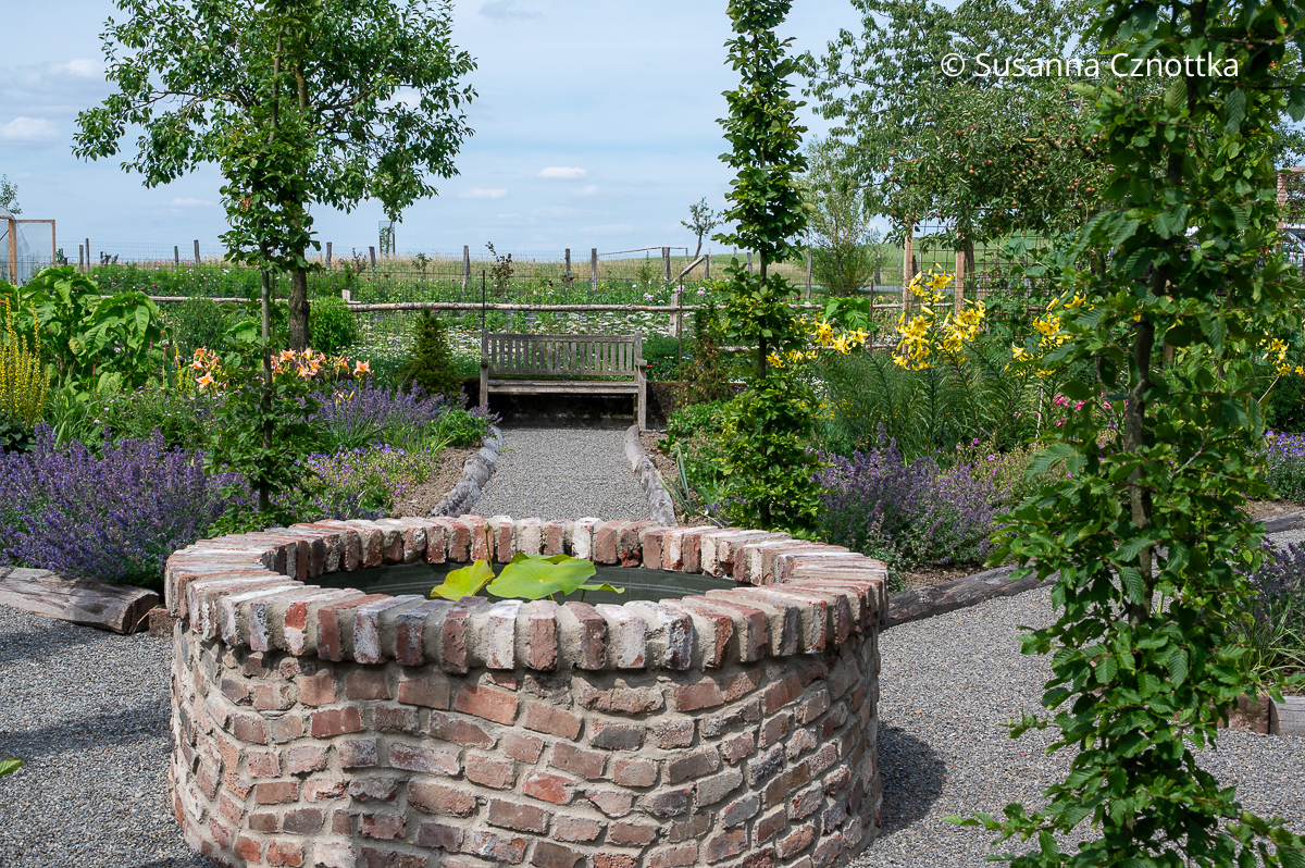 Fokuspunkte in der Gartengestaltung: ein gemauerter Brunnen und eine Bank