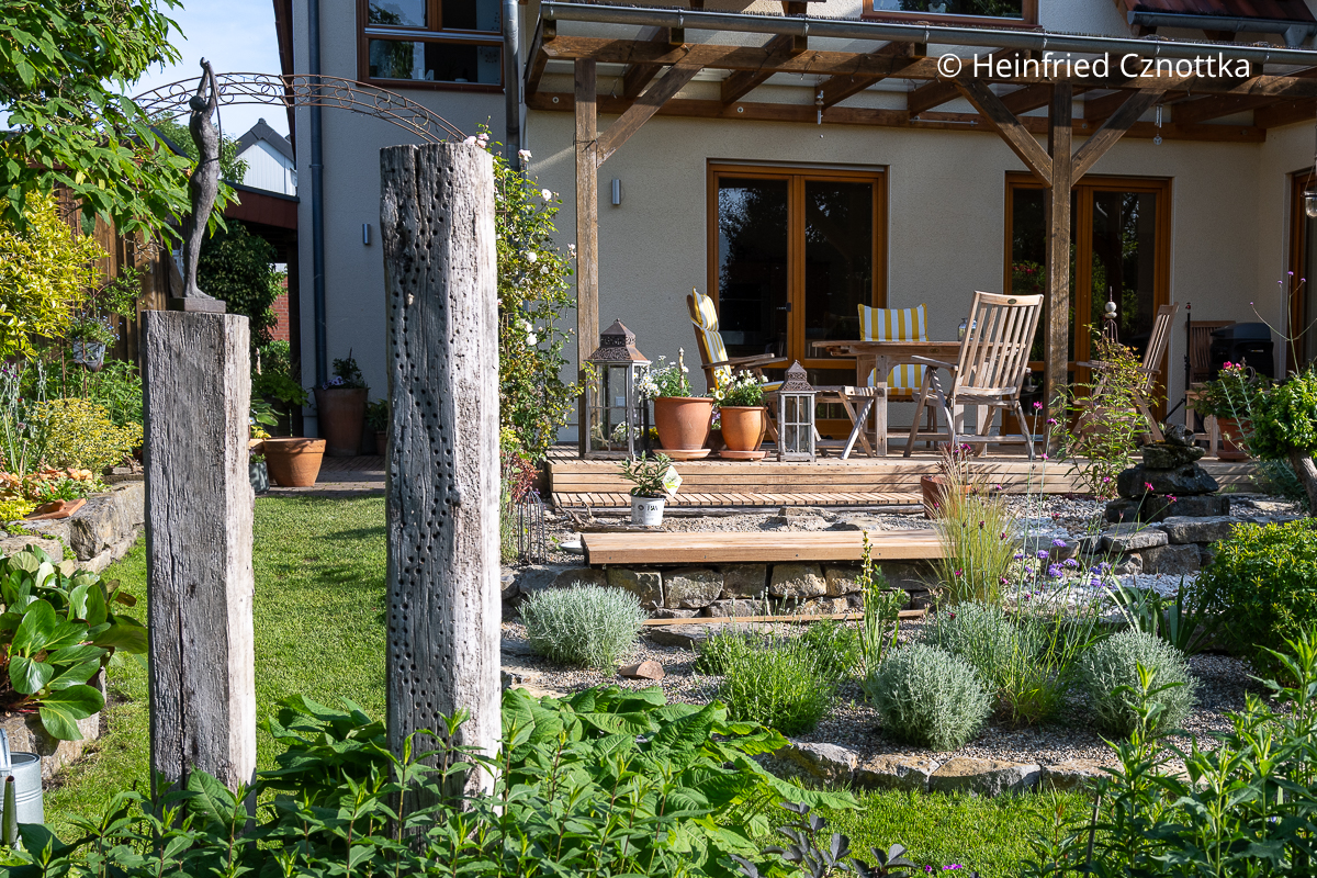 Blick auf eine Terrasse mit Beet und Insektenhotel davor Blick auf eine Terrasse mit Beet und Insektenhotel davor