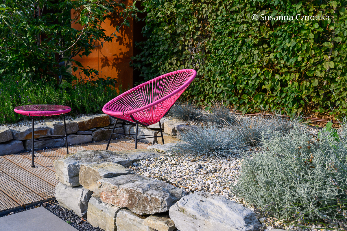 Mediterraner Garten: mit Kies, graulaubigen Pflanzen und dem pinkfarbenem Acapulco-Chair 
