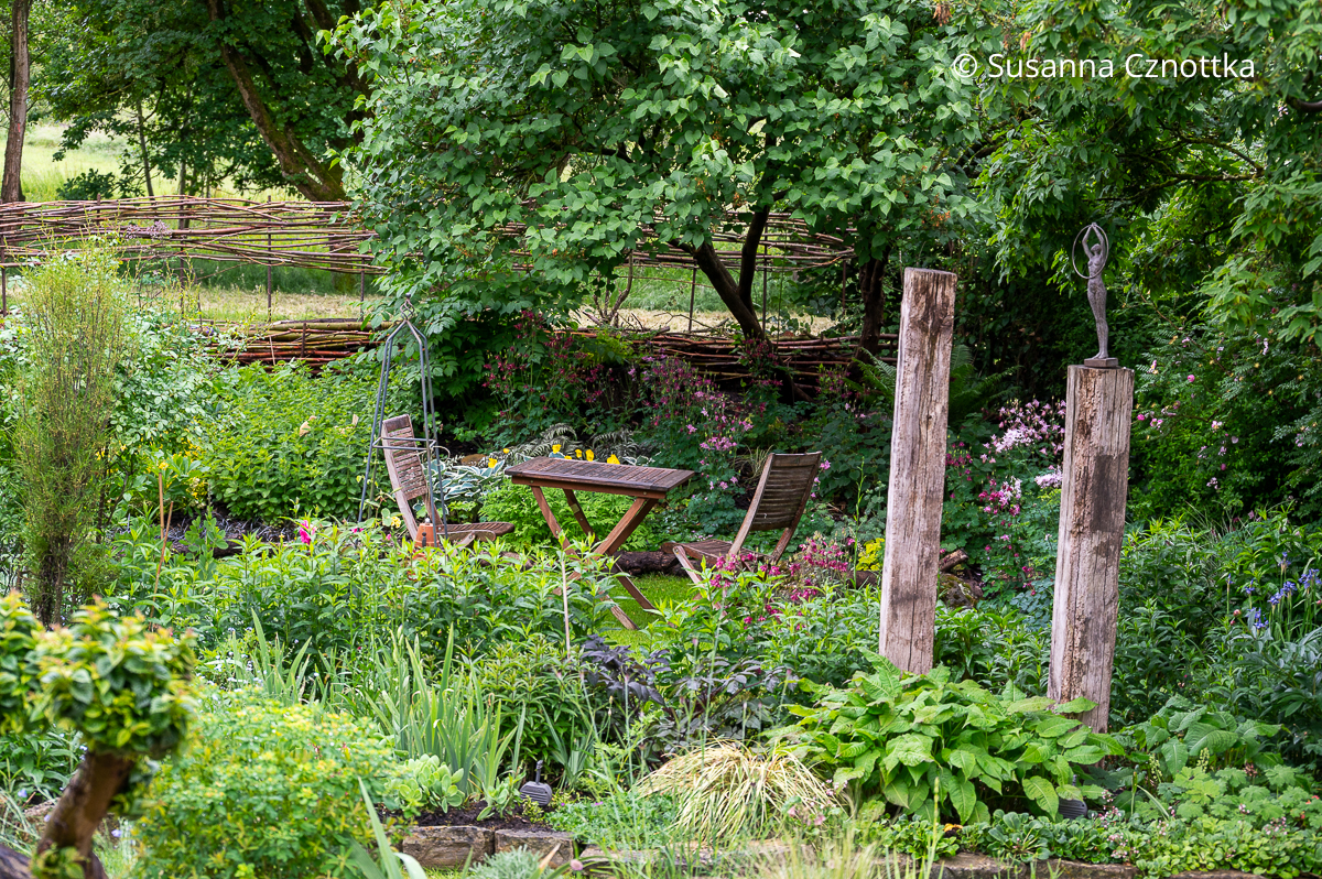 Zwei Eichenstelen und eine kleine hölzerne Sitzgruppe im Garten Zwei Eichenstelen und eine kleine hölzerne Sitzgruppe im Garten