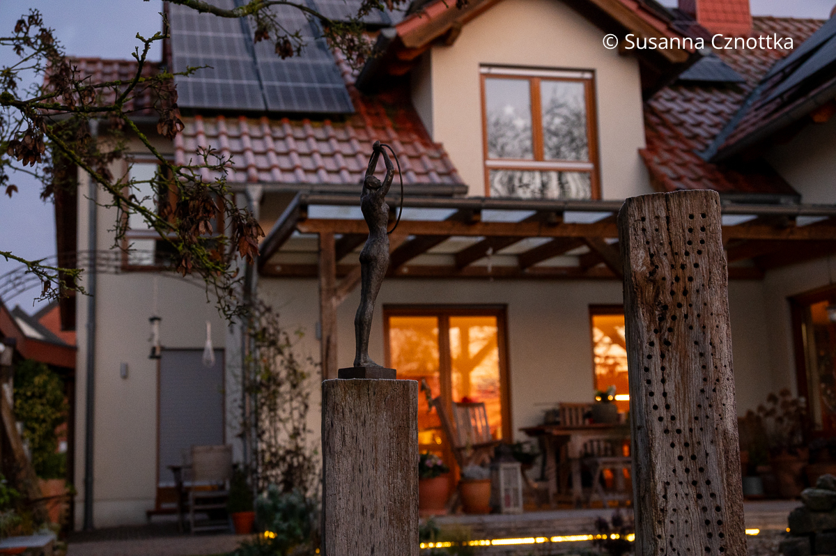 Blick auf das Haus mit beleuchteten Fenstern vom Garten aus