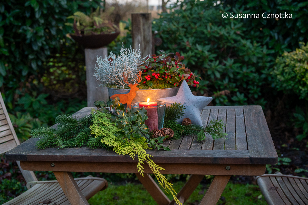 Weihnachtliche Gartendekoration mit Windlicht, Deko in Rostoptik und verschiedenem Grün