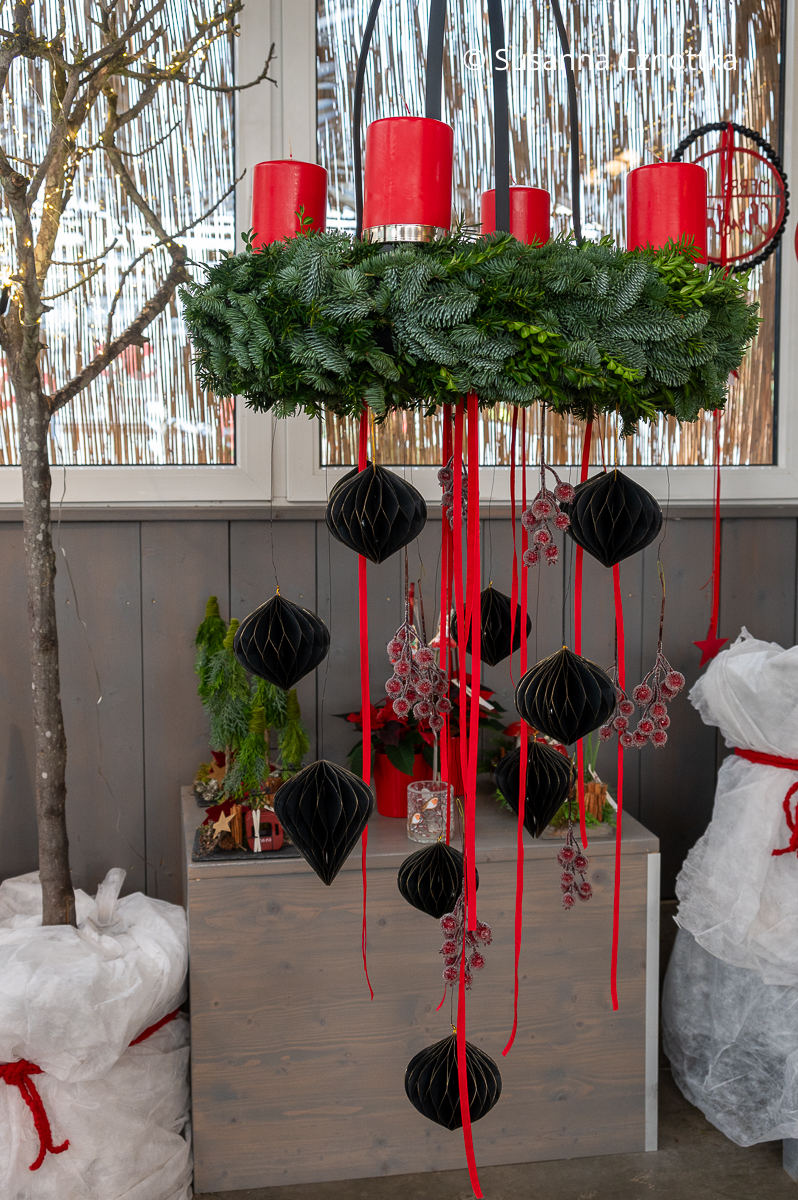 Hängender Adventskranz mit schwarzen Ornamenten und gefrosteten Beeren