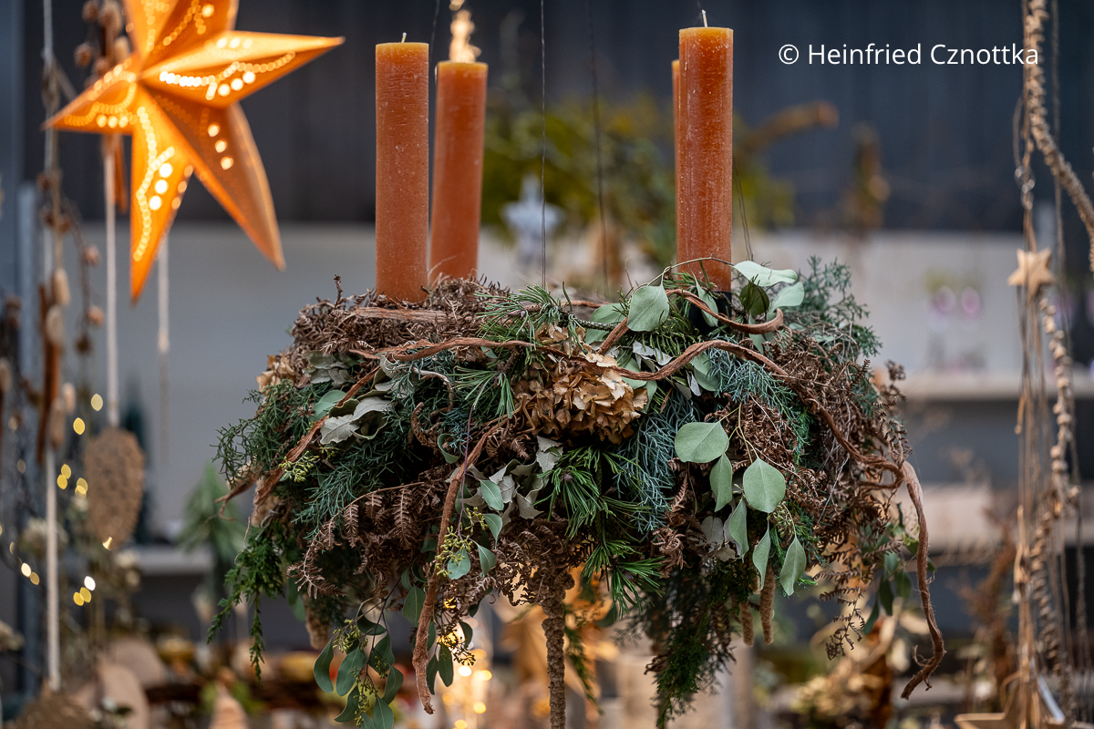 Natürlich wirkender Adventskranz mit ockerfarbenen Kerzen, getrockneten Farnwedeln und Hortensien