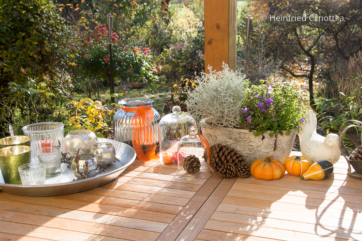 Herbstliche Terrassendekoration mit Kürbissen und Teelichten
