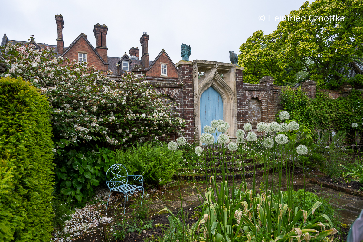 Romantik pur: eine hellblaue Tür, ein blauer Stuhl und cremeweiße Alliumbälle in einem Gartenraum Romantik pur: eine hellblaue Tür, ein blauer Stuhl und cremeweiße Alliumbälle in einem Gartenraum