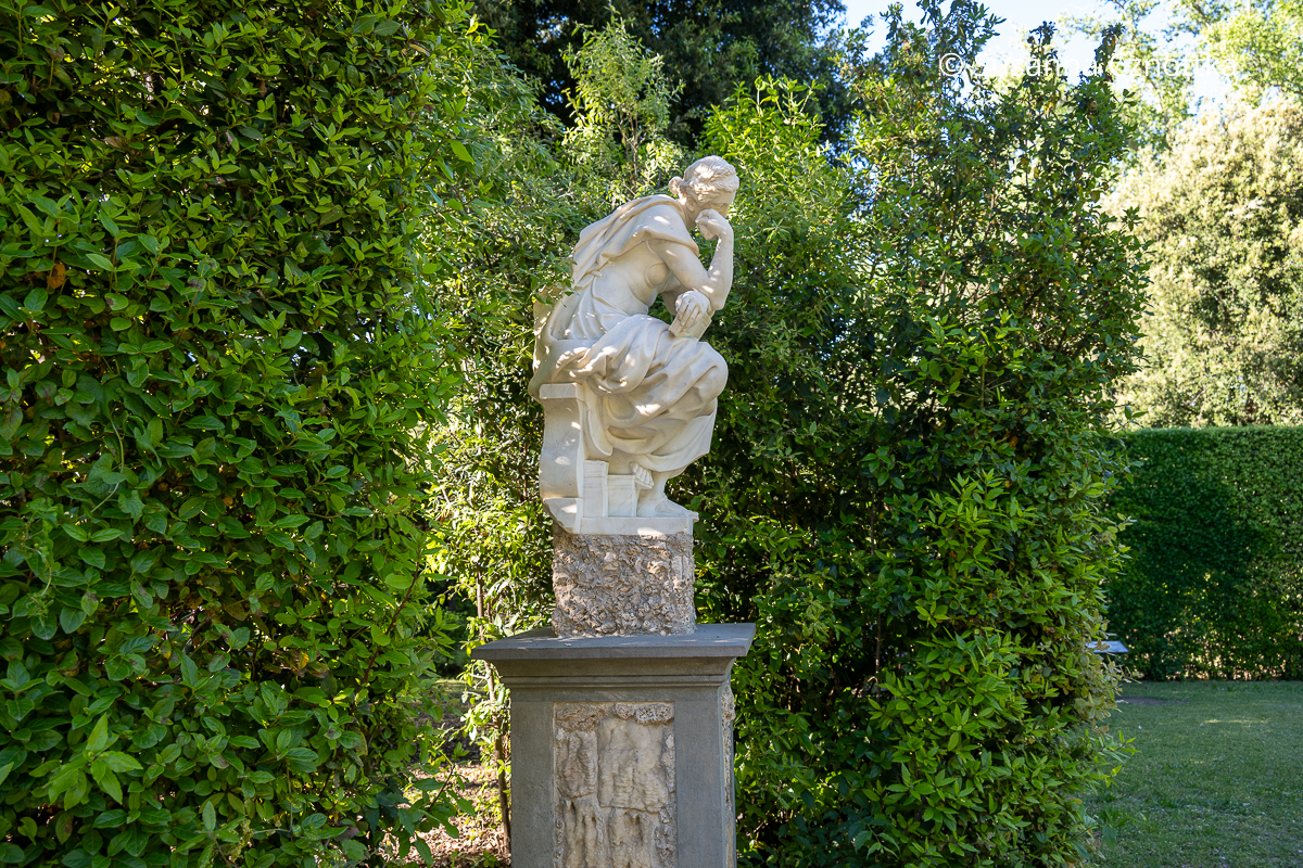 Eine weiße Marmorstatue, vermutlich eine Allegorie der Architektur Eine weiße Marmorstatue- eine sitzende Frau mit einem Buch in der Hand, den Kopf auf die andere Hand gestützt, vermutlich eine Allegorie der Architektur