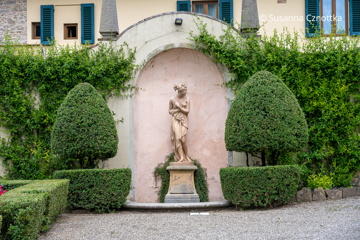 Eine Figur mit antiker Ausstrahlung zwischen zwei Formschnittgehölzen Eine Figur mit antiker Ausstrahlung in einer Wandnische zwischen zwei Formschnittgehölzen