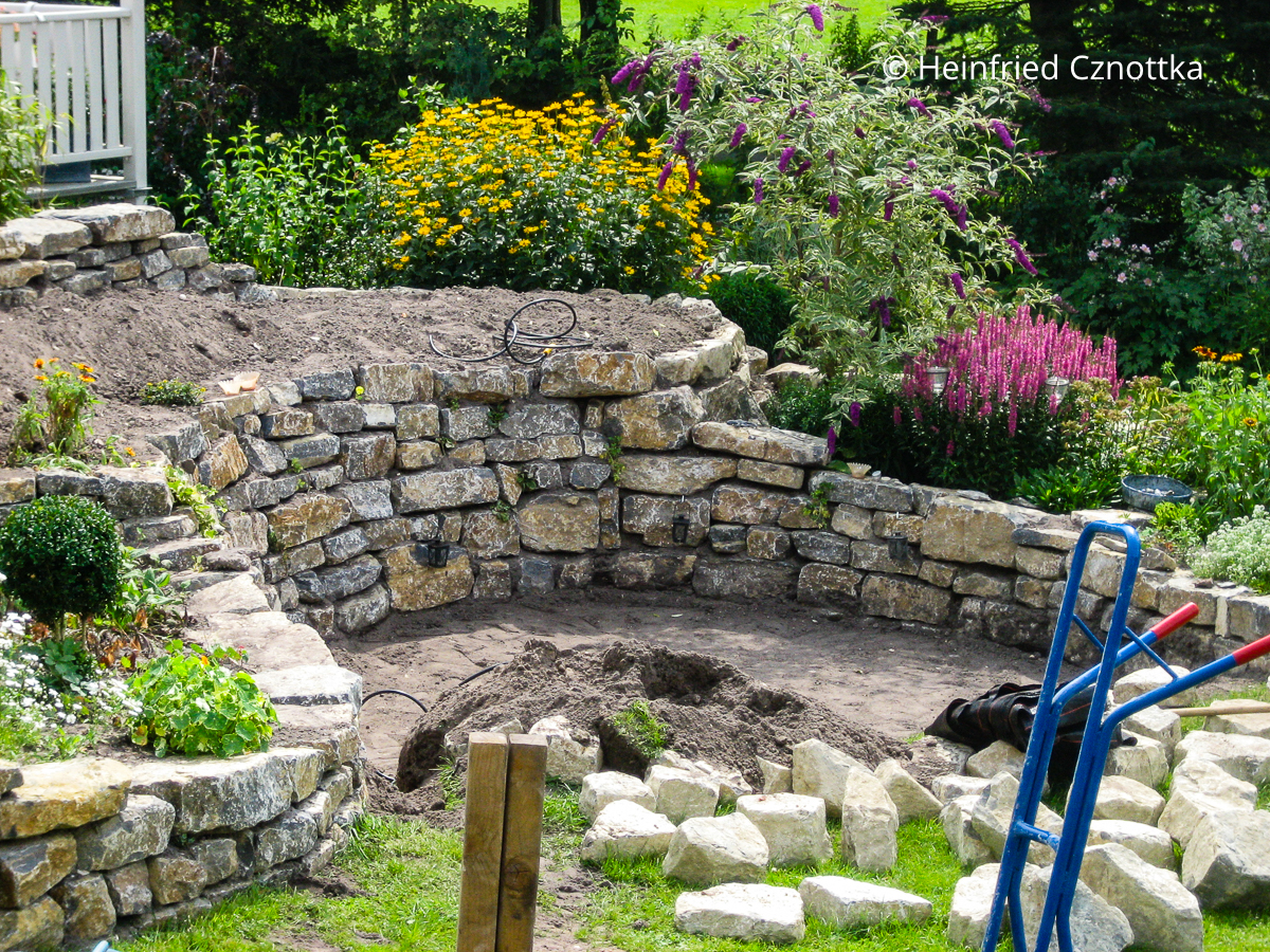 Ein Senkgarten mit einem Hochbeet aus Natursteinen entsteht