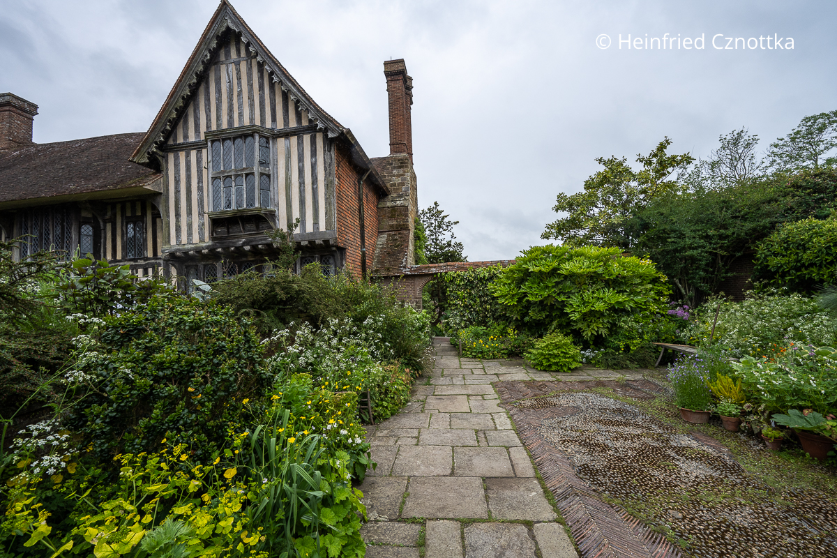 Blick in den Wall Garden am Herrenhaus Great Dixter mit einer stattlichen Zimmeraralie und einem Mosaik aus Kieselsteinen