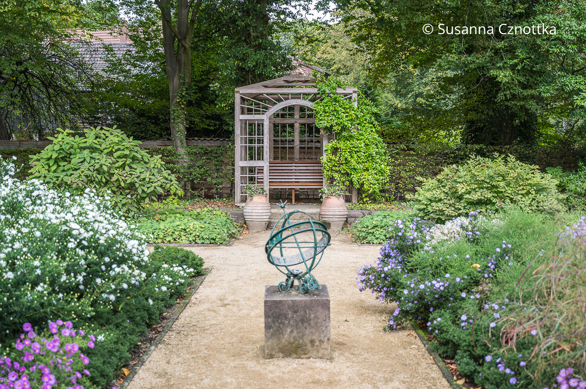 Fokuspunkt: eine Laube am Ende eines Gartenweges