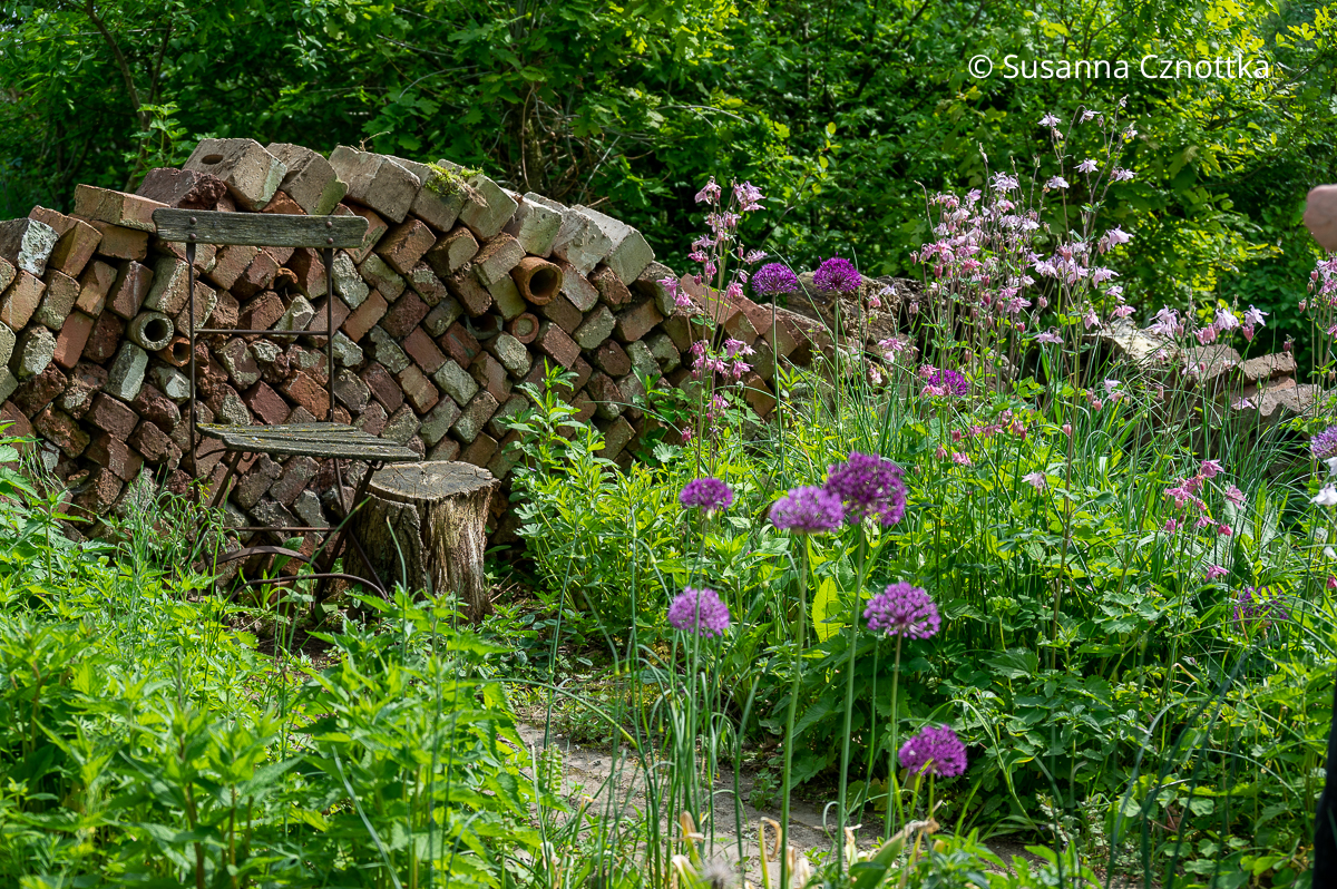 Upcycling im Garten: Eine Mauer aus alten Backsteinen begrenzt einen Gartenraum