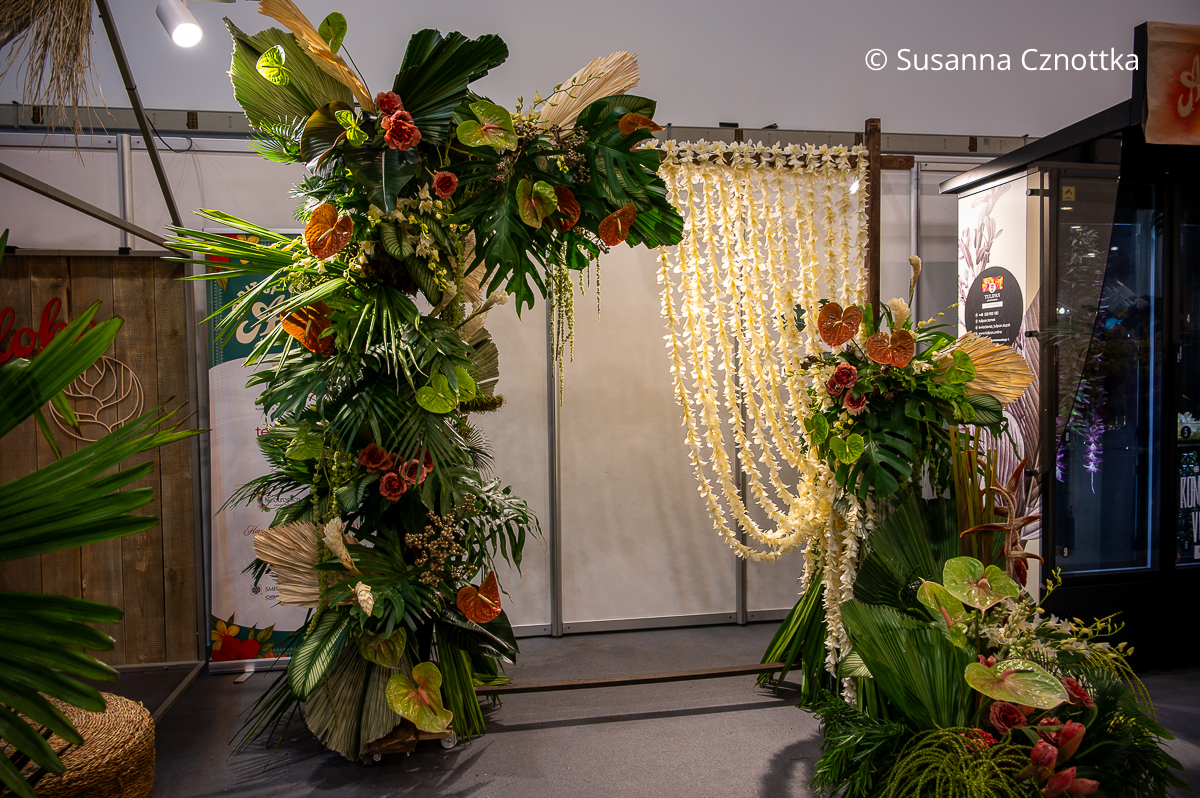 Aloha-Gefühl: eine üppige Girlande aus Palmwedeln, Anthurien und Philodendronblättern und ein Vorhang aus Blumenketten