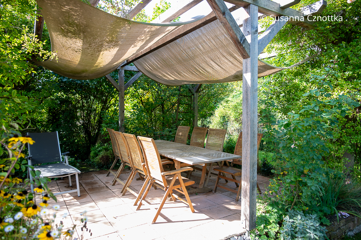 Sitzplatz im Garten: eine lange Tafel unter einer Pergola Sitzplatz im Garten: eine lange Tafel unter einer Pergola