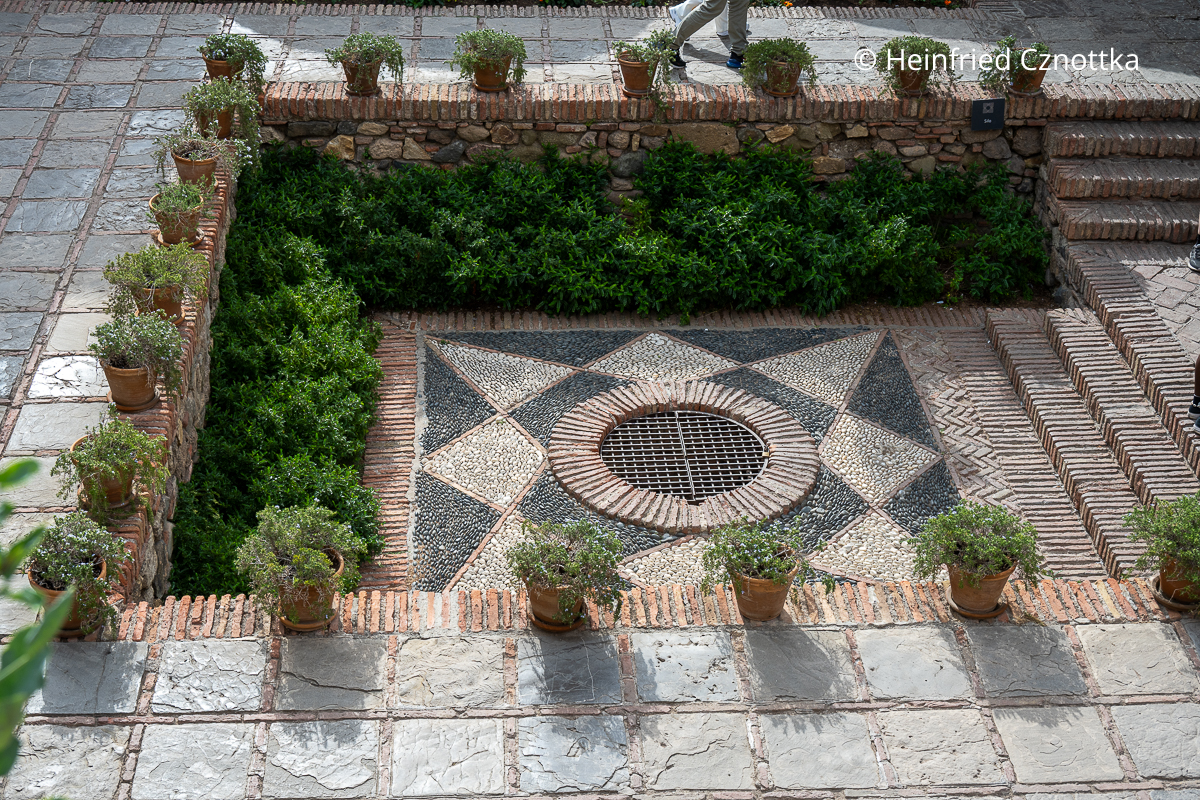 Ein kleiner tiefer liegender Bereich in der Alcazaba in Málaga mit einem sternförmigen Mosaik aus Flusskieseln