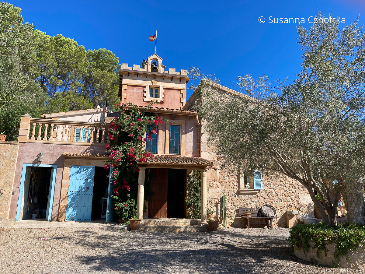 Blaue Türen und Fensterläden und eine Bougainvillea an der Fassade einer Finca auf Mallorca