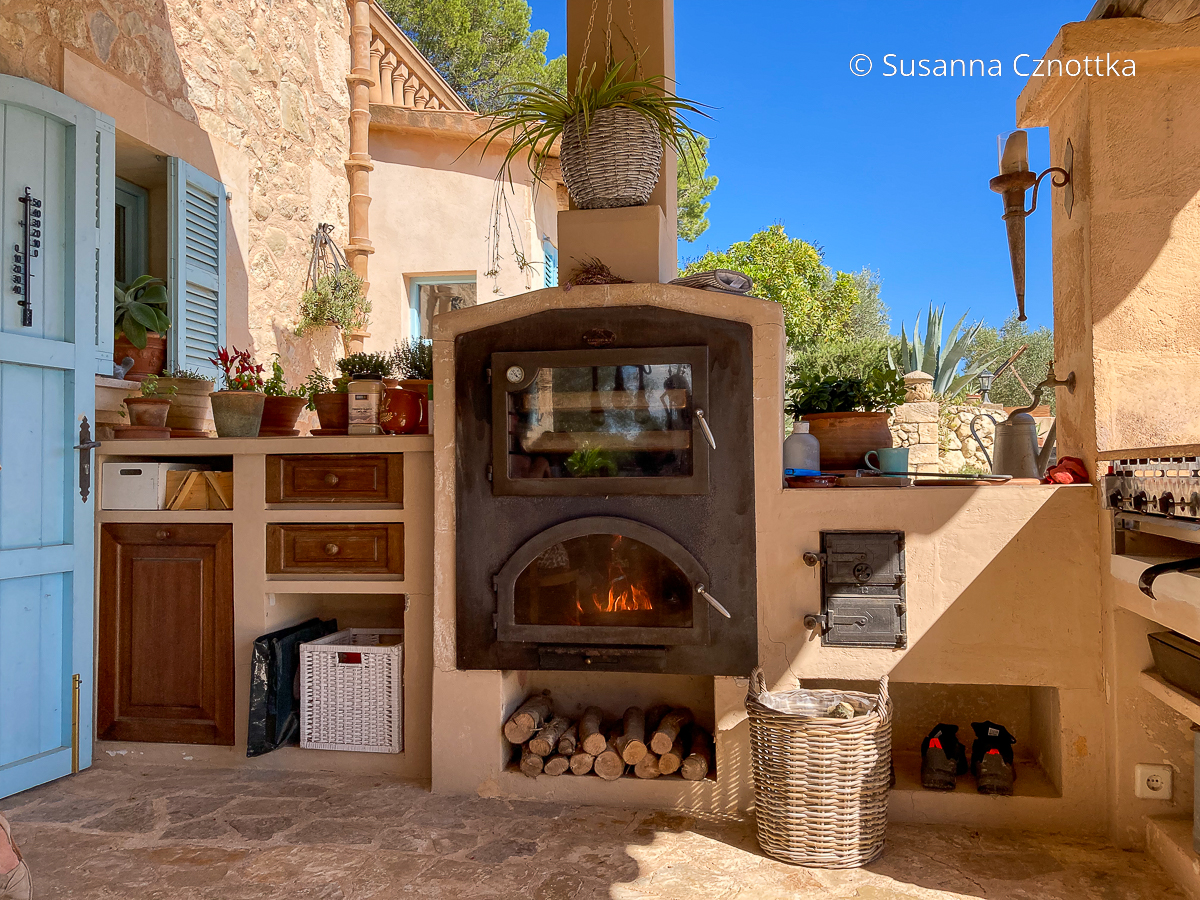 Finca auf Mallorca: Outdoorküche mit einem Ofen, in dem ein Feuer brennt