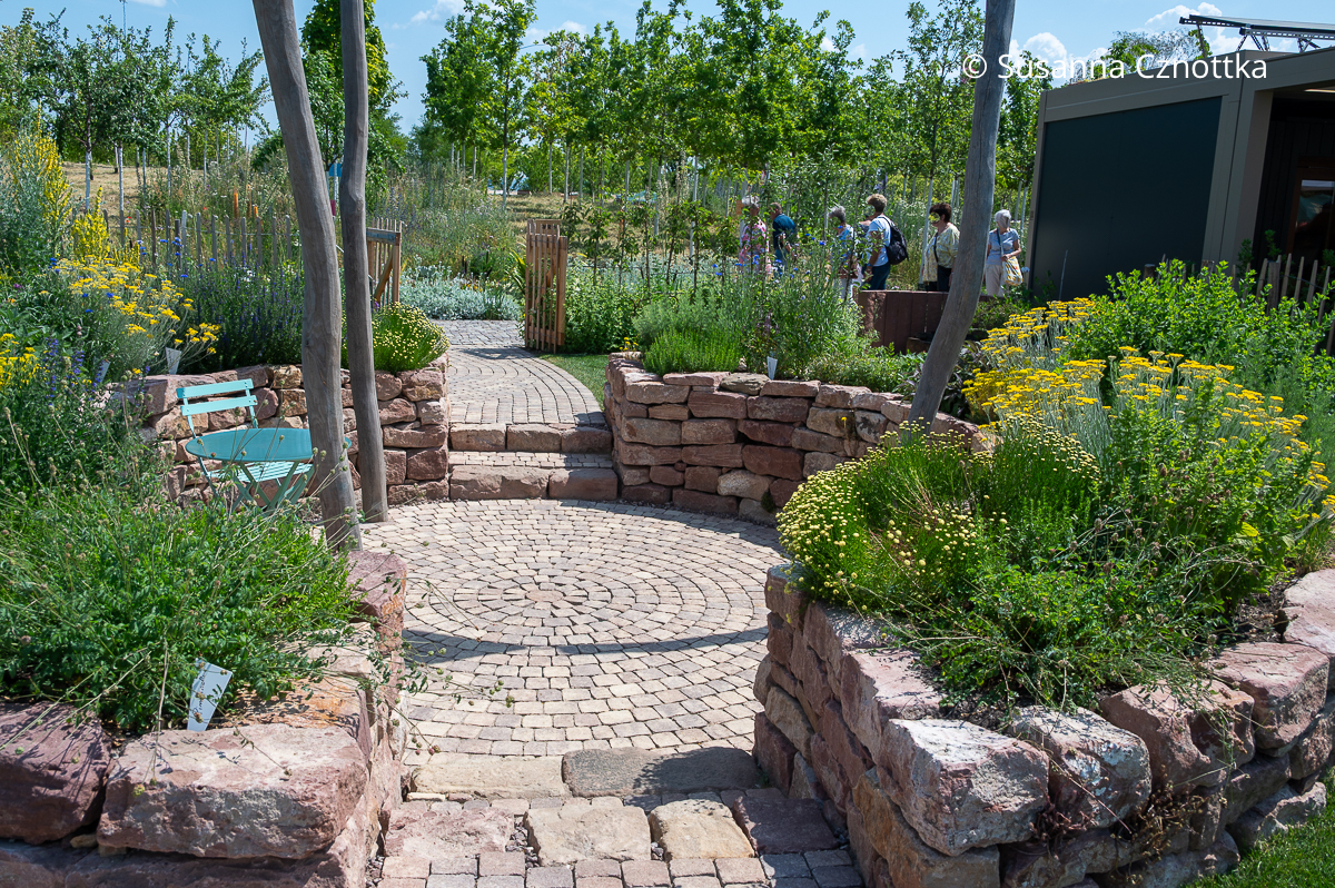 Ein mit Kräutern bepflanzter Senkgarten mit Natursteinmauern