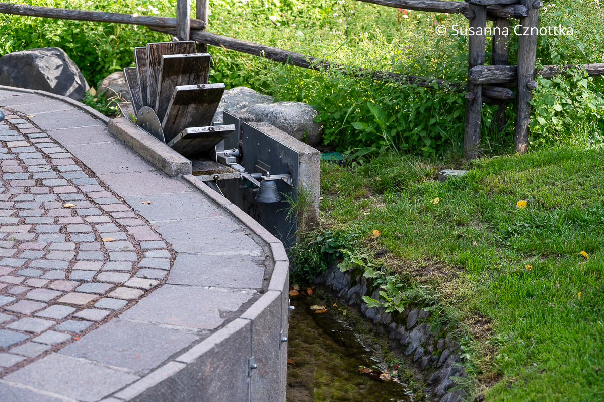 Sogenannter "Waal", ein Bewässerungskanal in Südtirol mit einem Wasserrad und einer Glocke aus Metall