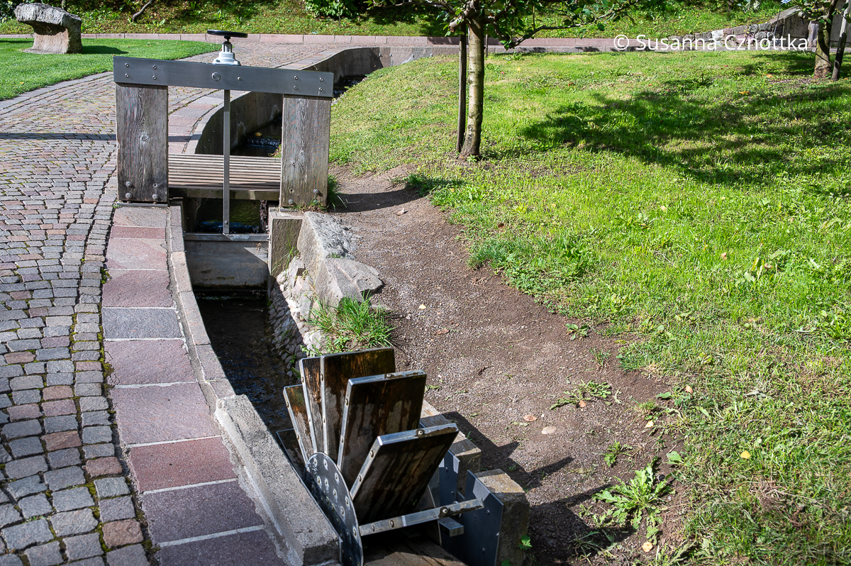 Sogenannter "Waal", ein Bewässerungskanal in Südtirol mit einem Wasserrad und einer Stauvorrichtung aus Holz und Metall