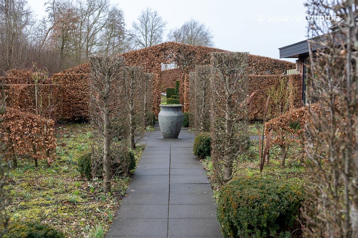 Fokuspunkt: eine große markante Vase in einem winterlichen Gartenraum