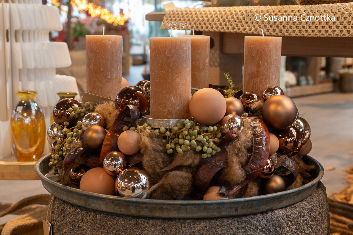 Ein Adventskranz in warmen Brauntönen mit matten und glänzenden Kugeln, Dattelfrüchten und Schoten des Lederhülsenbaumes (Gleditsia triacanthos)