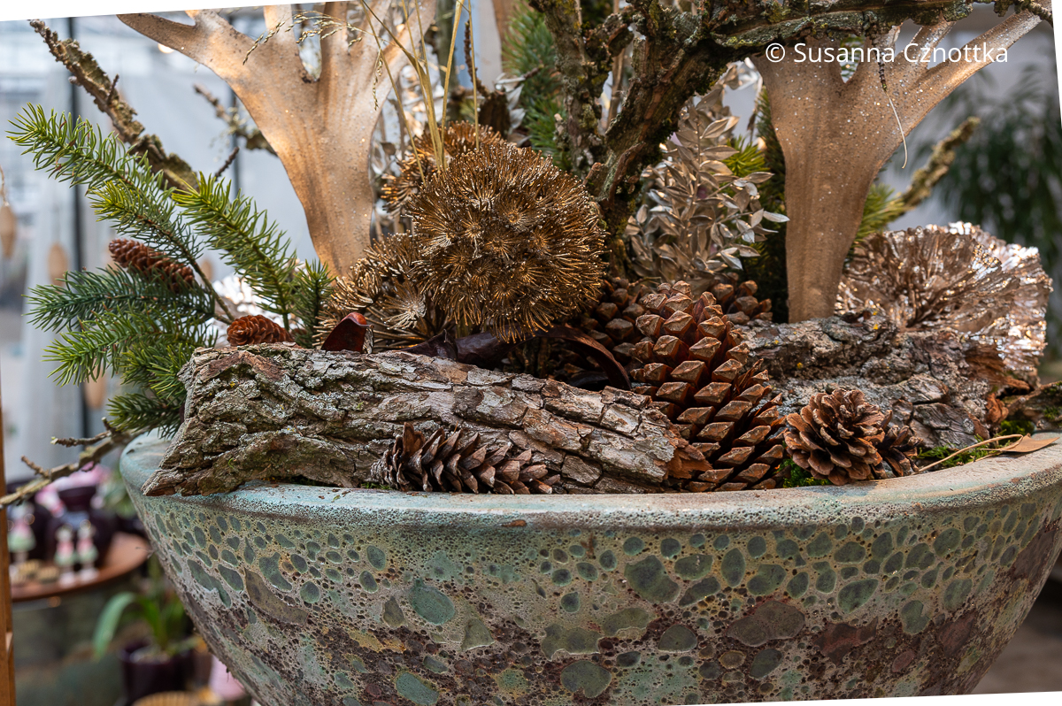 Detail eines Adventsgestecks mit Zapfen, Rinde und in Gold angesprühten Samenständen