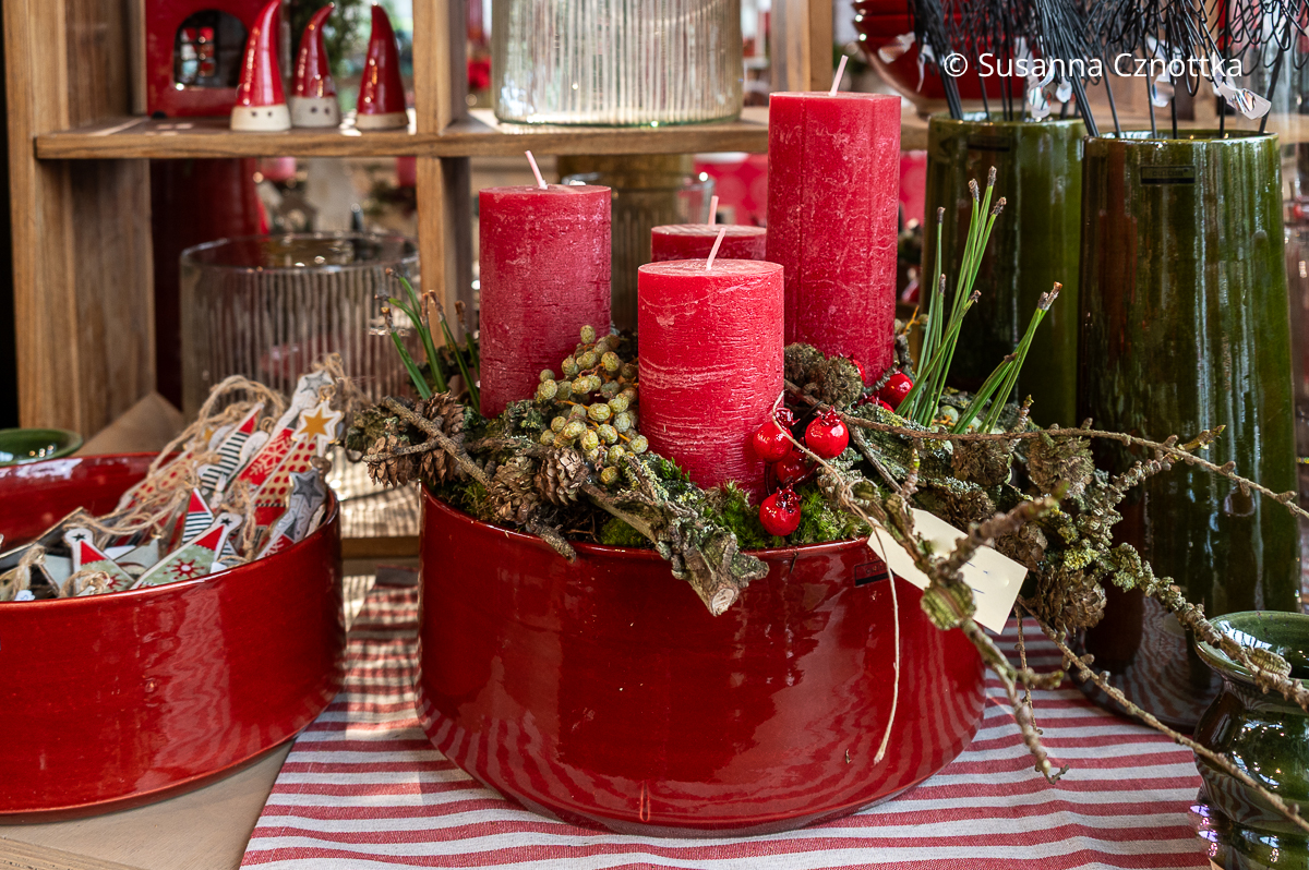 Ein Adventsgesteck in einer roten Schale mit dicken roten Stumpenkerzen