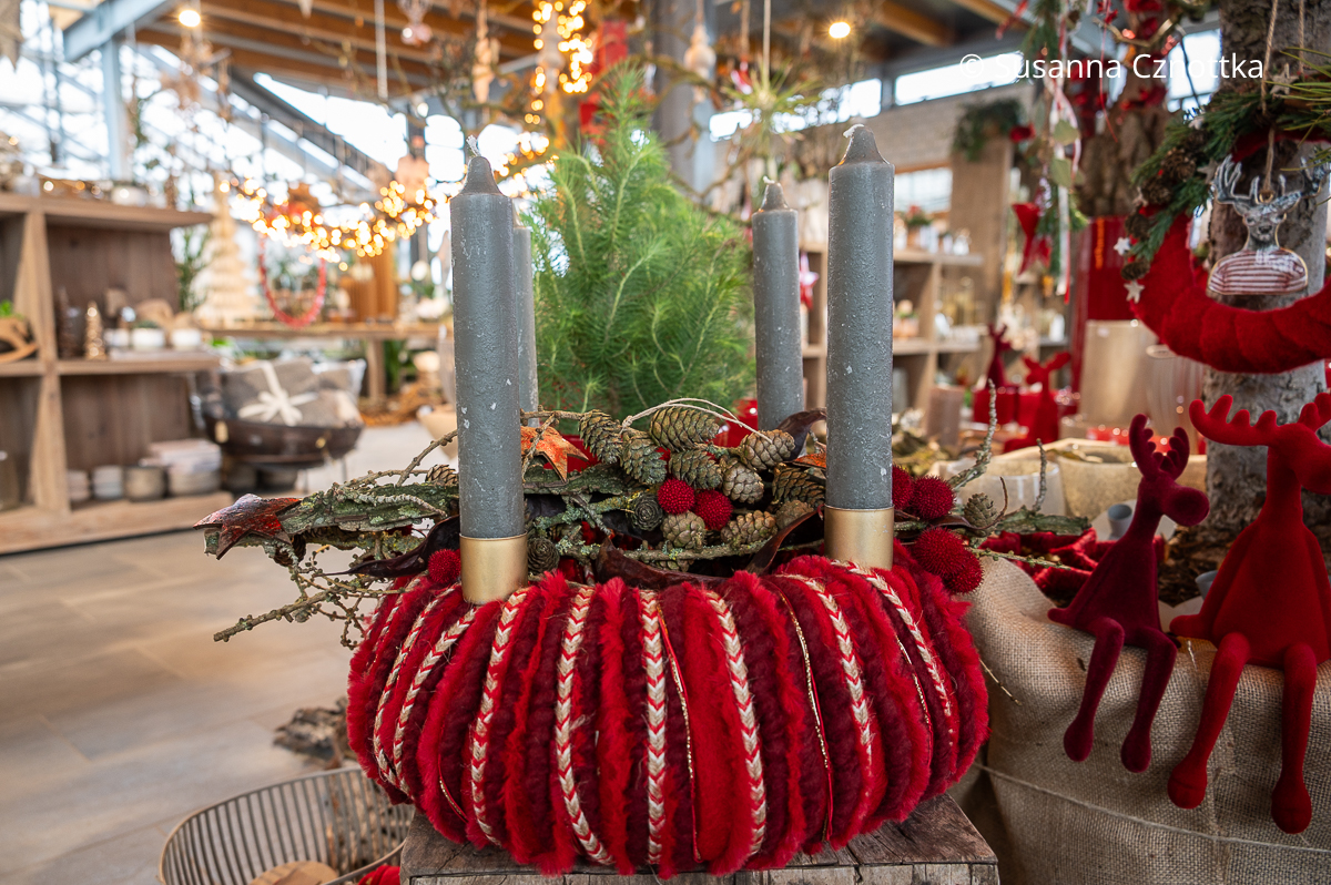 Adventsfloristik: Kranz auf einer Filzunterlage mit verschiedenen Bändern in Rottönen und vier grauen Stabkerzen