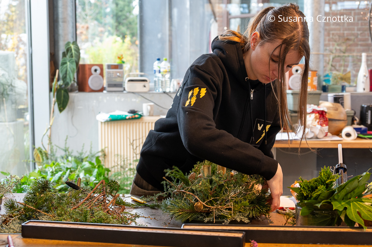 Eine Frau arbeitet an einem Adventsgesteck