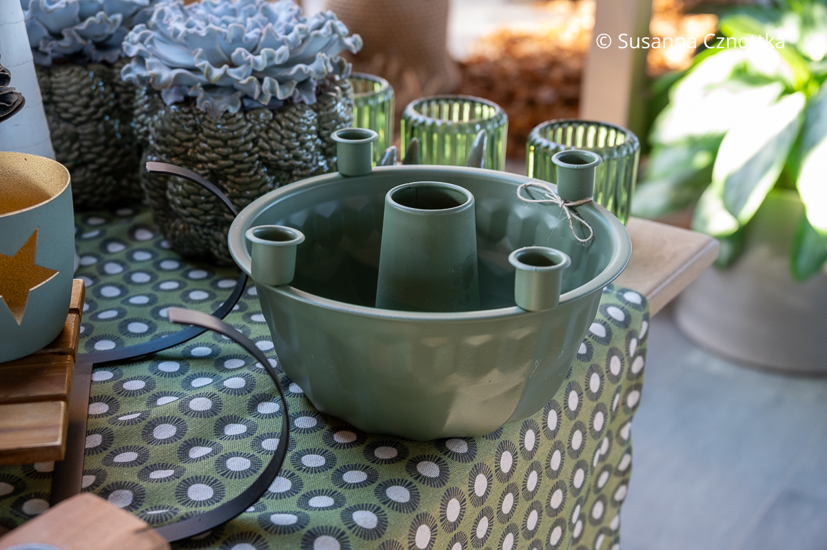 Eine salbeigrüne Gugelhupfform mit  vier Halterungen für Stabkerzen auf dem Rand