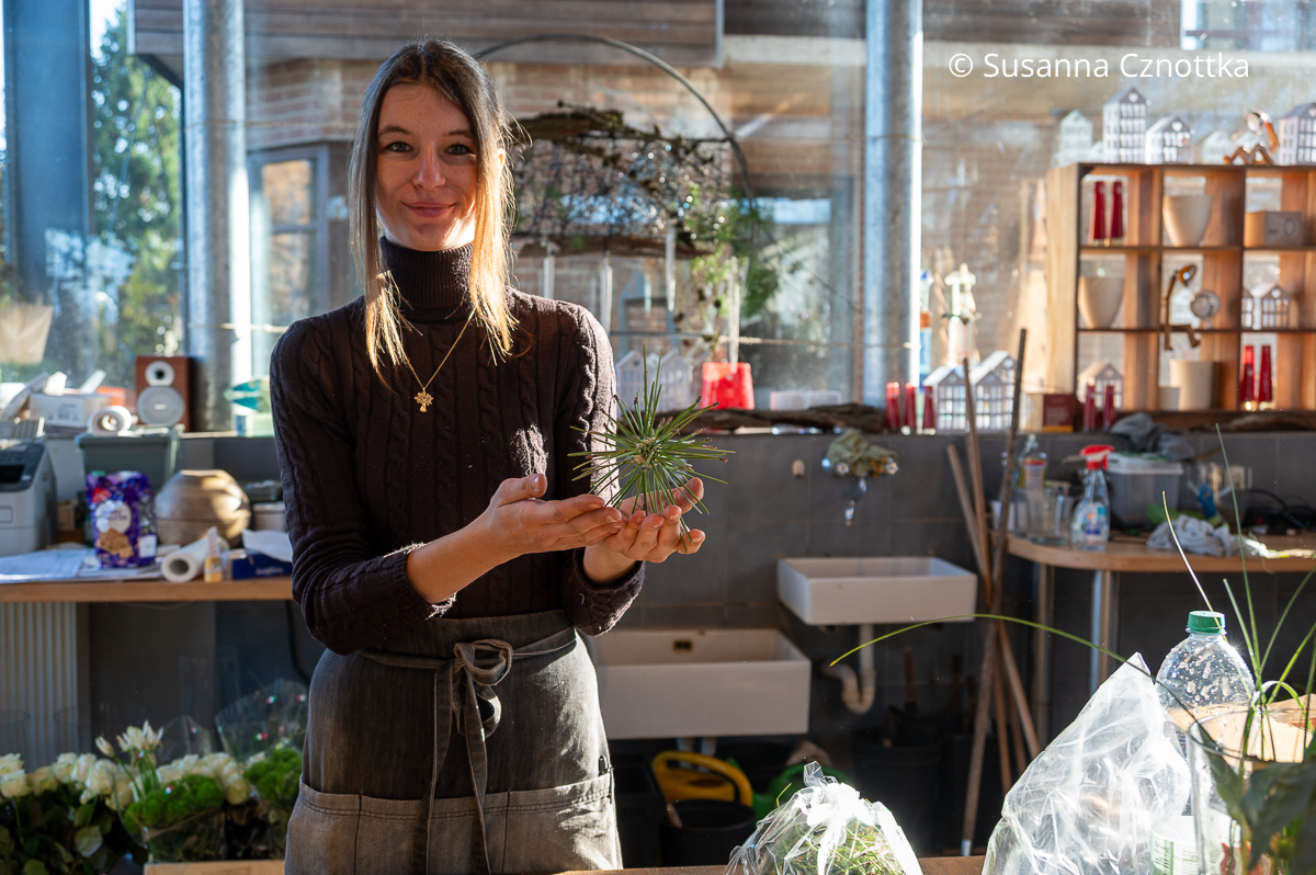 Eine junge Frau hält einen Stern aus Draht und Piniennadeln in den Händen