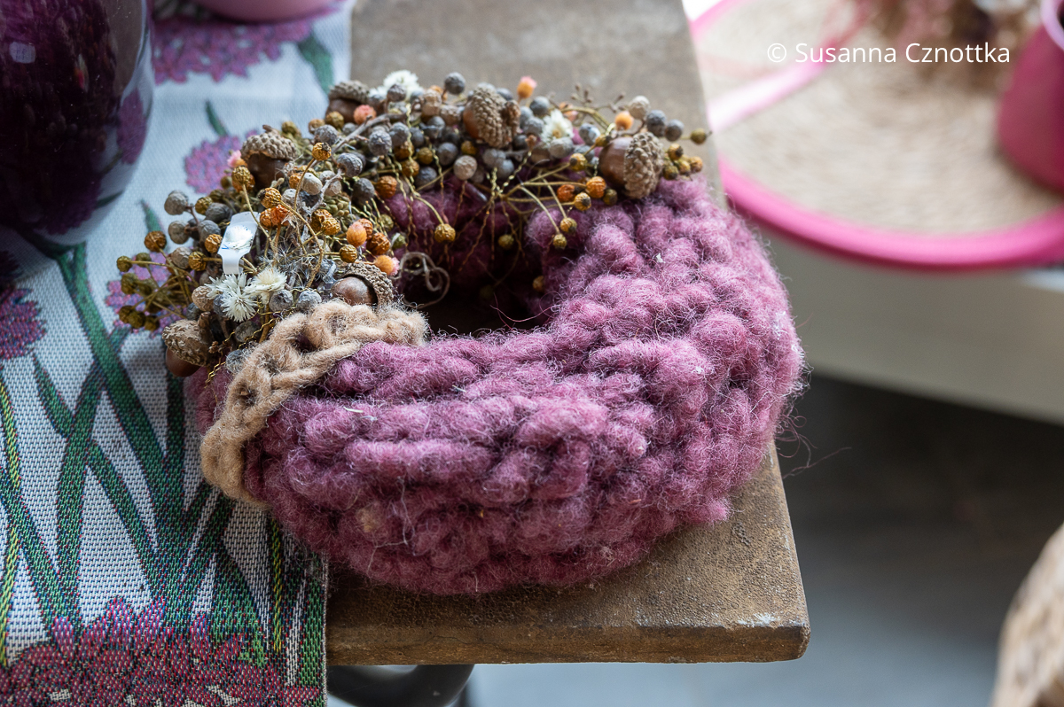 Ein violetter Filzkranz mit kleinen, silbernen und goldenen Früchten Ein violetter Filzkranz mit kleinen, silbernen und goldenen Früchten