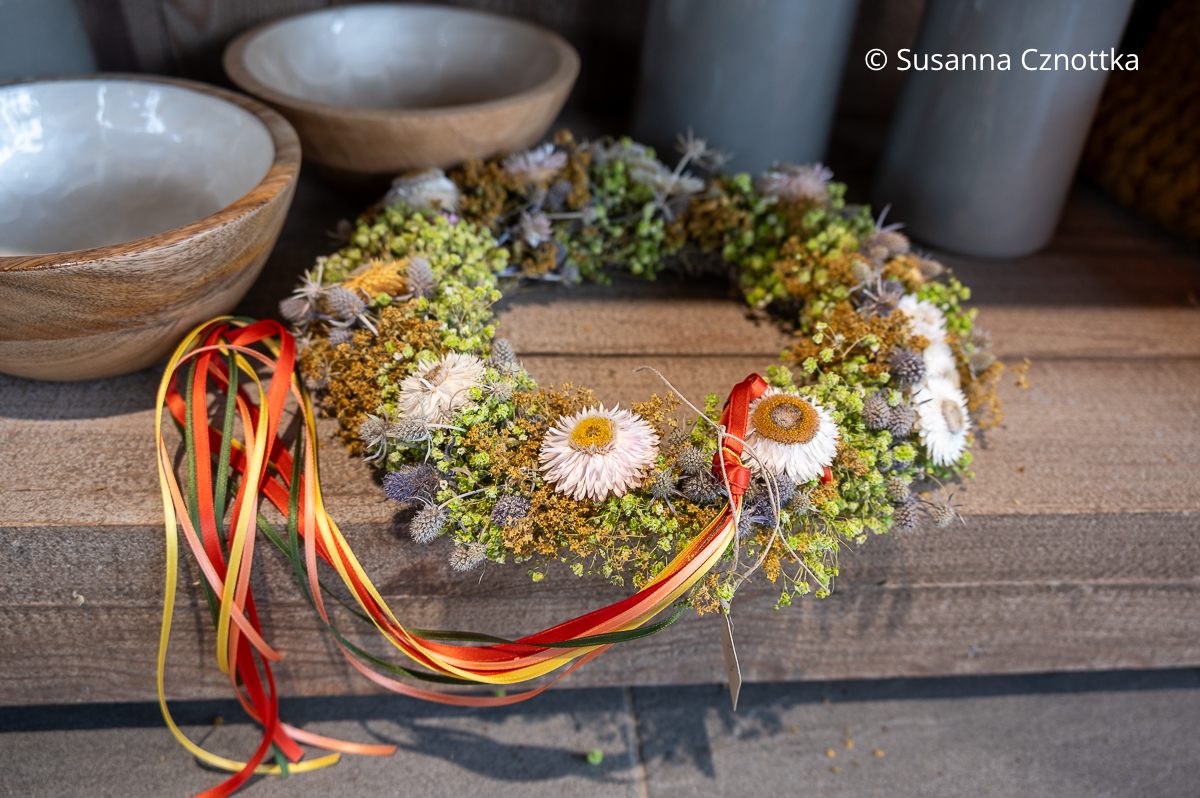 Kranz mit weißen Strohblumen und blauen Blüten von Edeldisteln