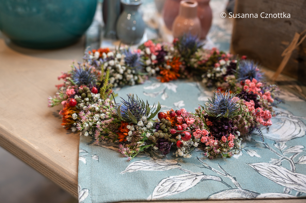 Kränzchen mit winzigen Hagebutten und den blauen Blüten einer Edeldistel Kränzchen mit winzigen Hagebutten und den blauen Blüten einer Edeldistel