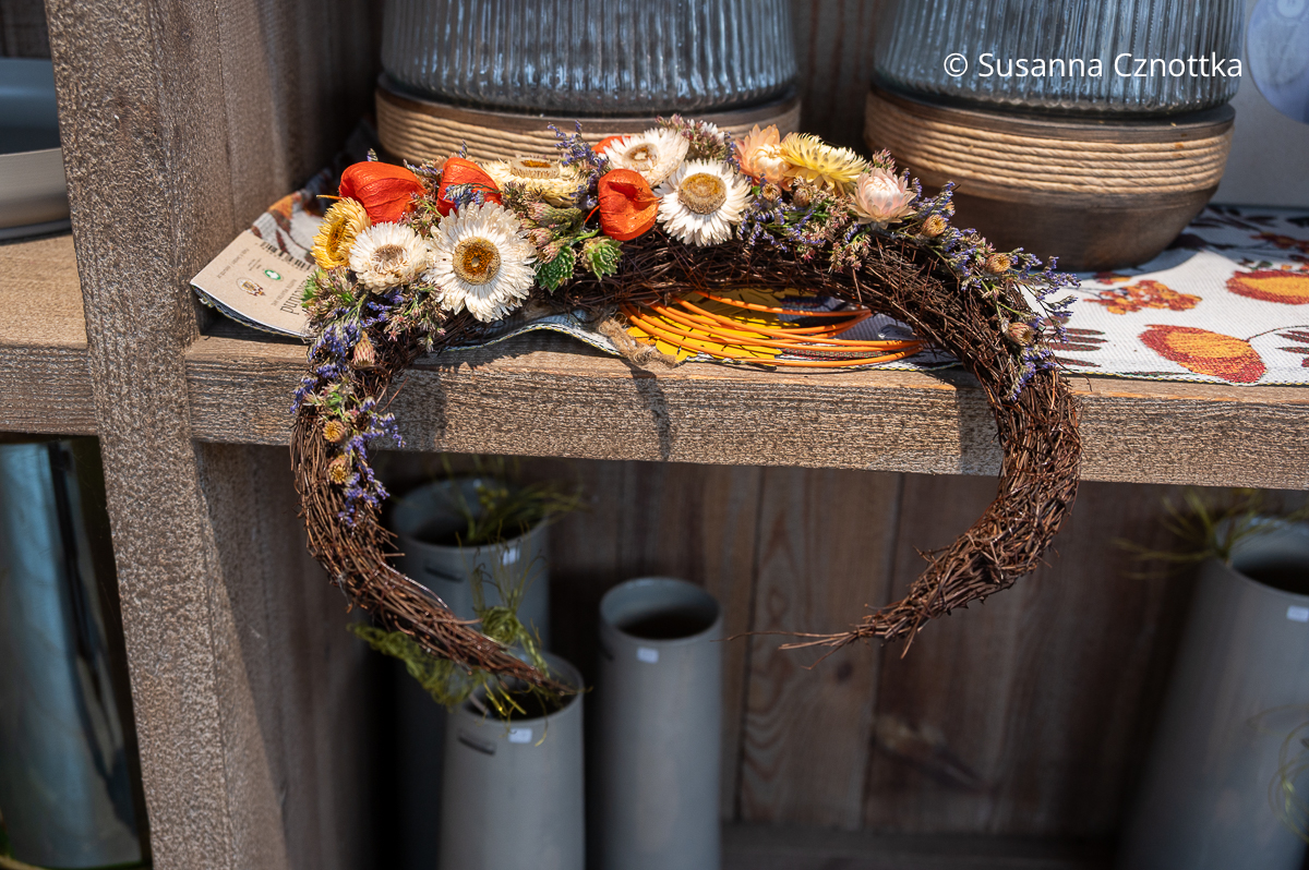 Ein mondförmiges floristisches Werkstück mit Strohblumen und Physalis Ein mondförmiges floristisches Werkstück mit Strohblumen und Physalis