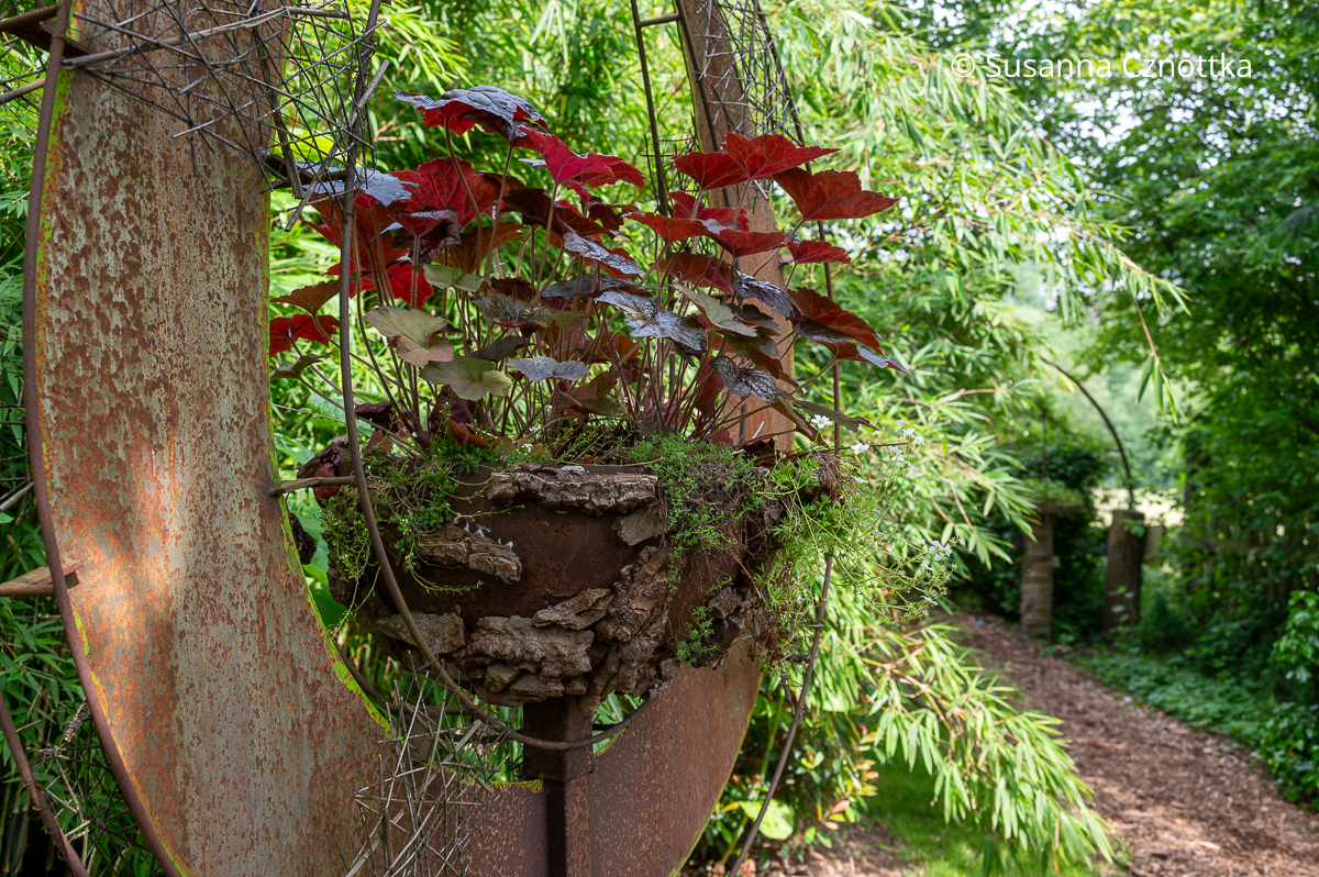 Bepflanztes Dekoobjekt in Rostoptik im Garten