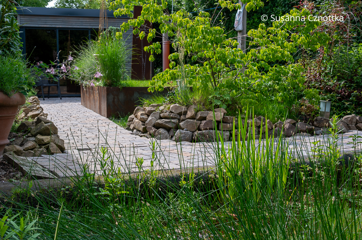 Versteckt: ein Saunahaus hinter einem Gartenbeet