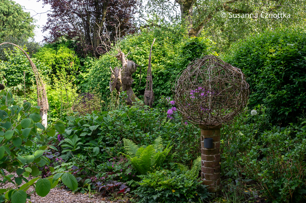 Floristische Objekte aus Weide und anderen Materialien in einem Garten