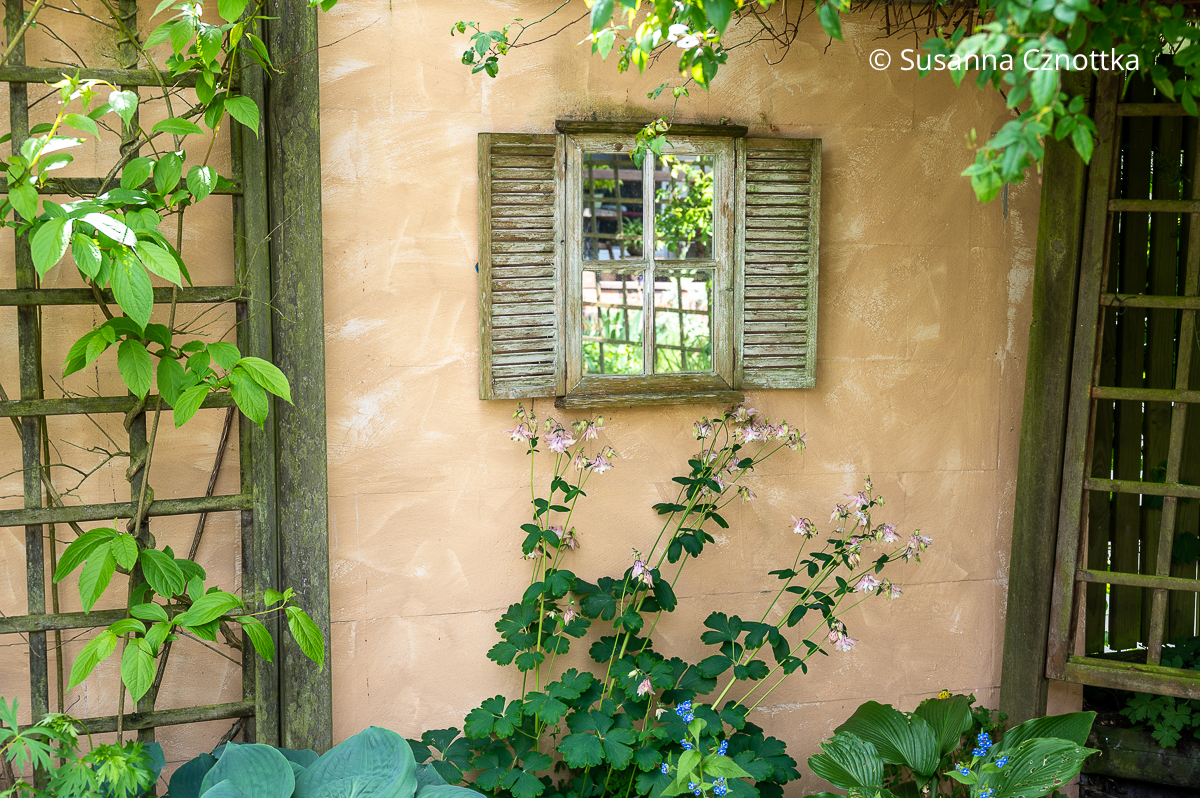 Verspiegeltes Fenster an einer Gartenmauer