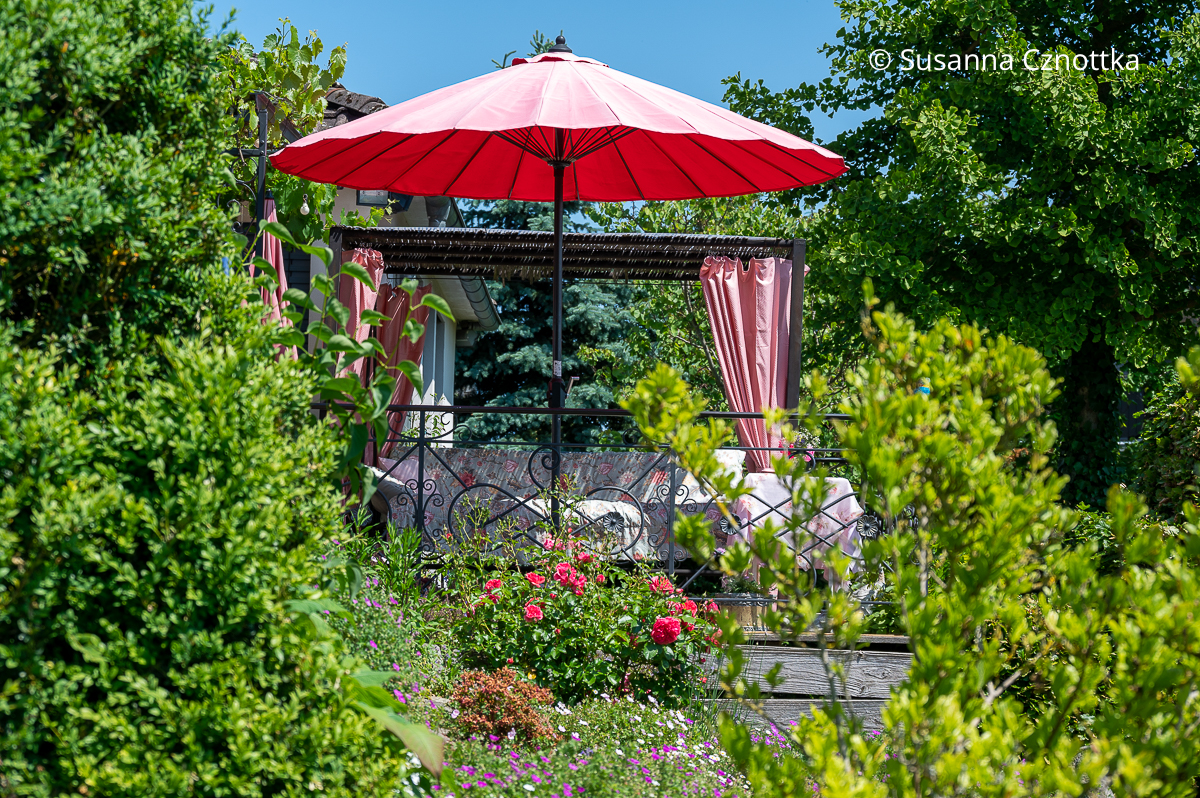 Sitzplatz im Garten: eine Hollywoodschaukel mit Sonnenschirm