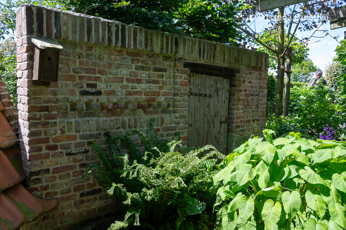 Gartenräume anlegen: eine Backsteinmauer im Garten