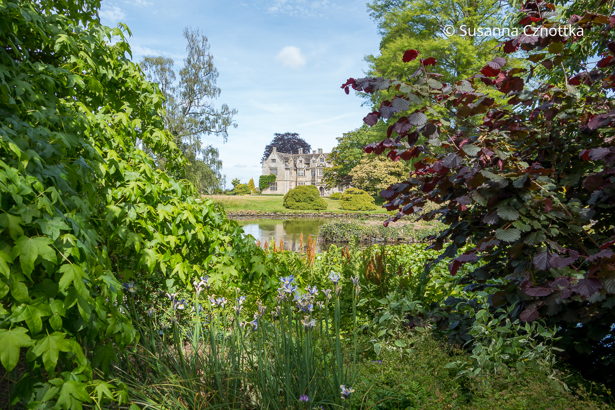 Blick über einen Teich auf das Herrenhaus in Wakehurst, Sussex